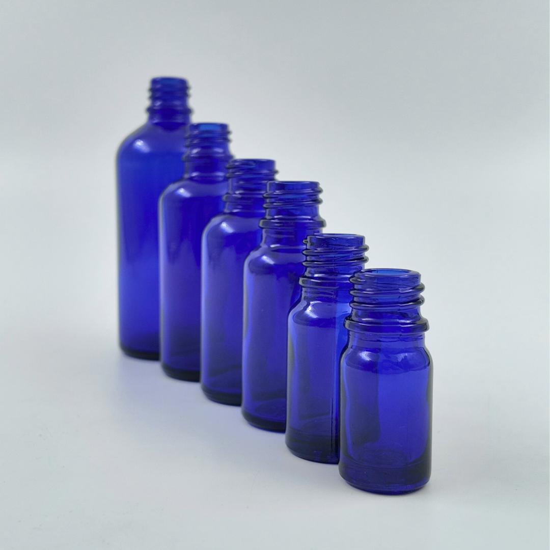 Lifestyle image of blue glass bottles in different sizes arranged on a surface