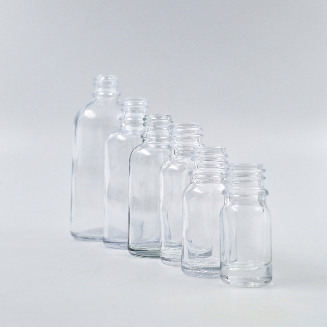 Lifestyle image of clear glass bottles in different sizes arranged on a surface