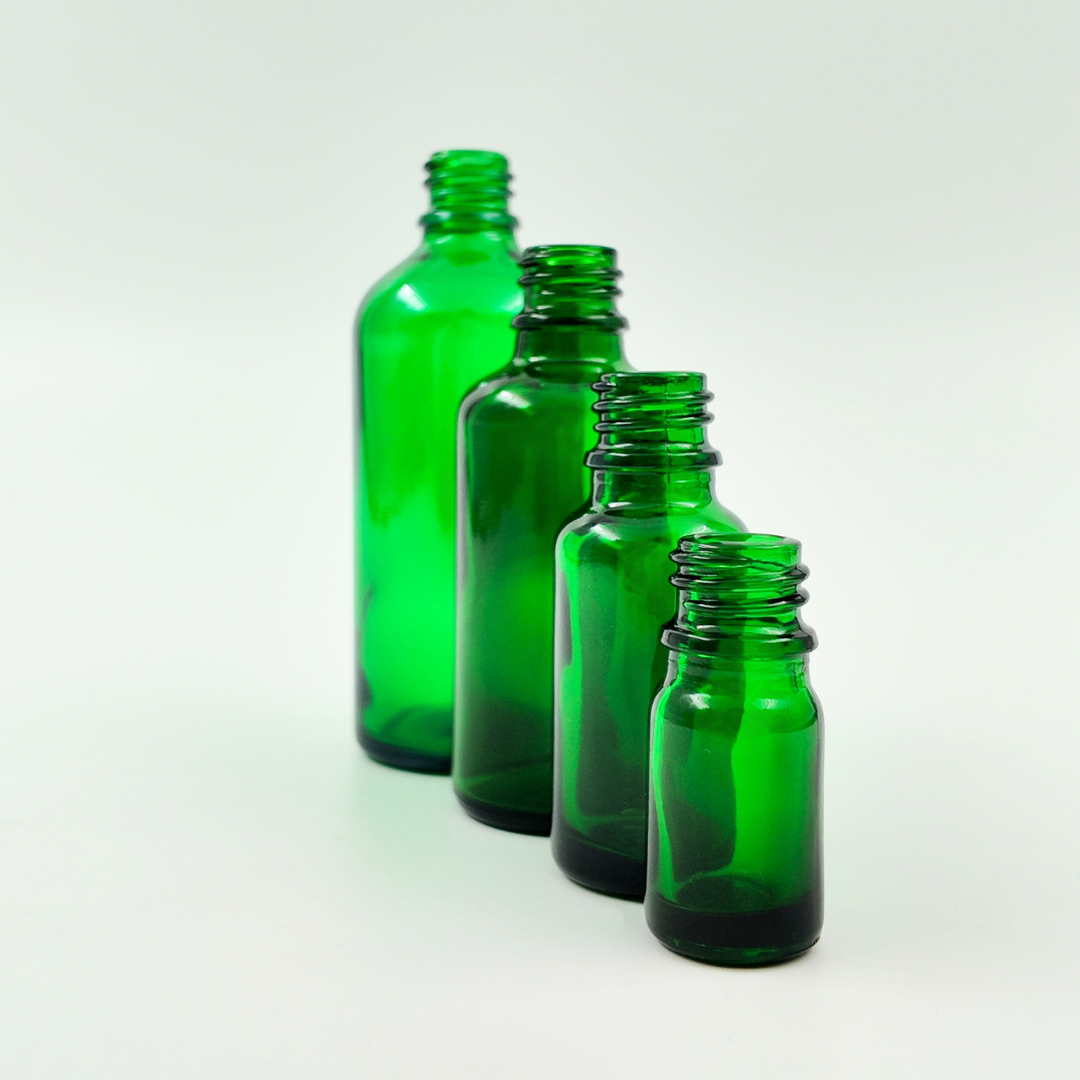 Lifestyle image of green glass bottles in different sizes arranged on a surface