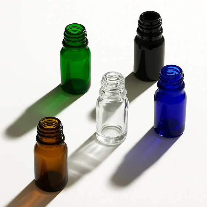 Five glass bottles of varying colors (green, clear, black, brown, blue) on a white background
