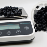 Electronic balance scale with blueberries on a white background