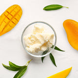 Top View Of Mango Butter In Glass Bowl Sorrounded By Sliced Mangoes And Leaves | Bulk Cosmetic Butters | Brightpack Raw Materials
